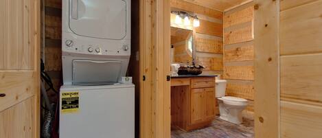 A compact wooden bathroom with a washing machine, a toilet, and a sink.
