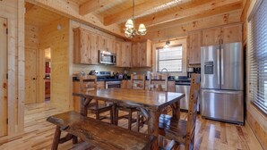 A wooden cabin-style kitchen with a central wooden table, built-in appliances, and a large refrigerator. - Lover's Hideaway by Jackson Mountain Rentals (Gatlinburg)