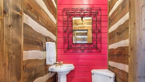 Une salle de bain avec des murs en bois, un lavabo blanc et des toilettes.