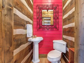 A bathroom with wooden walls, a white sink, and a toilet. - Little Bear by Jackson Mountain Rentals (Gatlinburg)