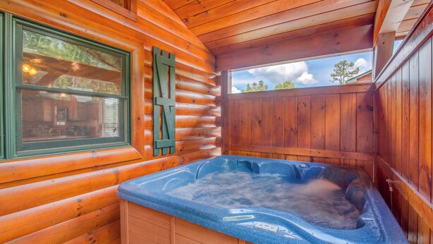 A wooden cabin with a hot tub, wooden walls, and a window with green shutters. - Magic Moments II by Jackson Mountain Rentals (Gatlinburg)