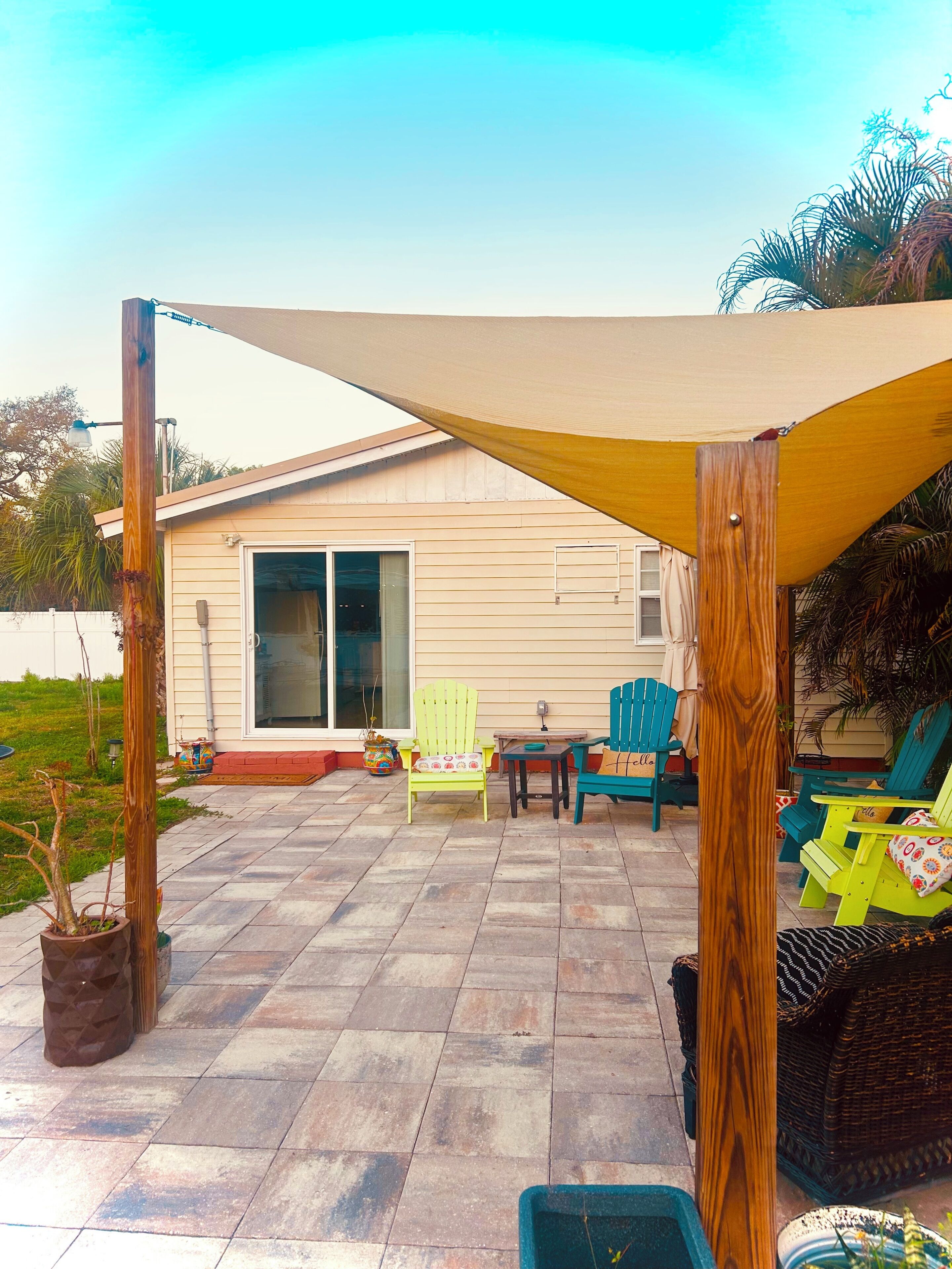 Un patio con mobiliario exterior, una pérgola de madera y una casa al fondo.
