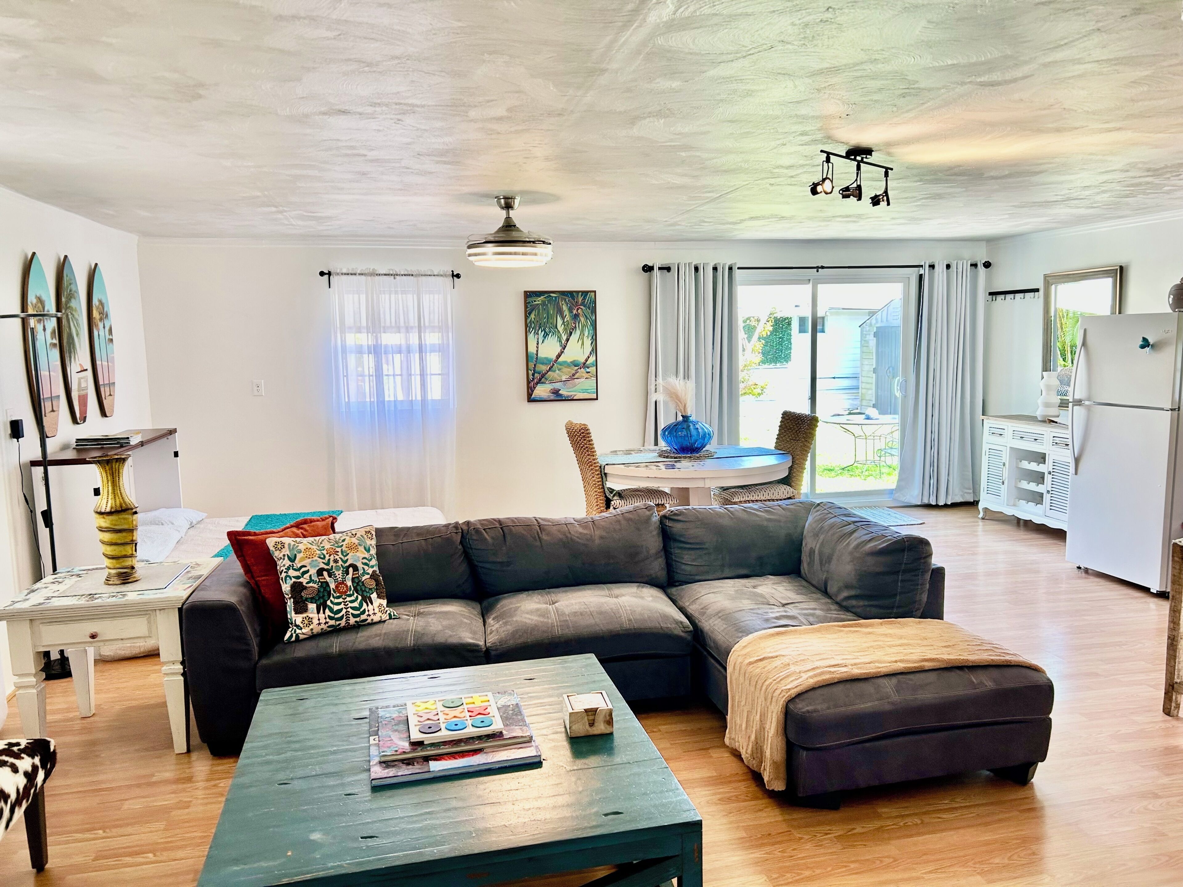 A modern living room with a sectional sofa, a coffee table, and a dining area with a table and chairs.