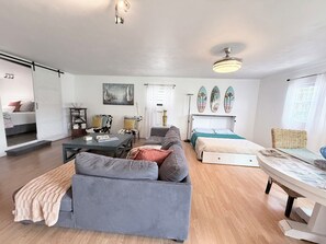 A modern living room with a sofa, a coffee table, a dining table, and a ceiling fan.