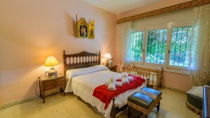 Un dormitorio con una cama de madera, dos mesitas de noche con lámparas, una ventana con cortinas y un adorno en la pared.