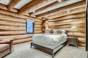 Une chambre située dans une cabane en rondins, avec un lit, des tables de chevet et une fenêtre.