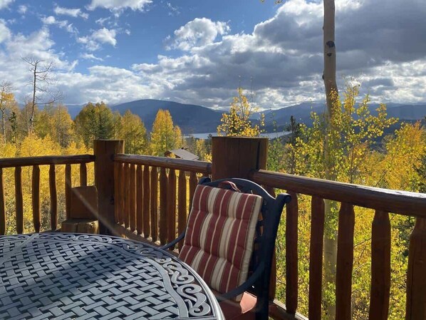 A wooden deck with a table and chairs, overlooking a mountainous landscape.