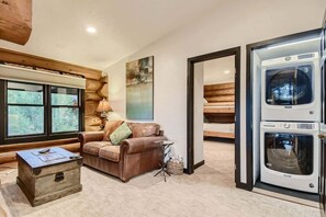 A cozy living room with a leather couch, a wooden chest, and a washing machine. - Private Hot Tub in Amazing Home Away From Home! (Silverthorne)