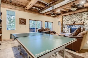 A ping pong table labeled 'BRUNSWICK' in a room with stone walls, wooden ceiling beams, and a fireplace.