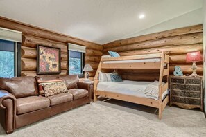 Ein gemütliches Zimmer mit einem Etagenbett, einer Ledersofa und einem Holzkoffer.