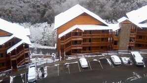 Una cabaña con varios balcones y un estacionamiento con varios coches.