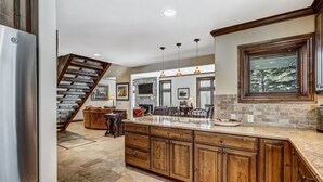 A kitchen with a large island, wooden cabinets, and a stone backsplash.