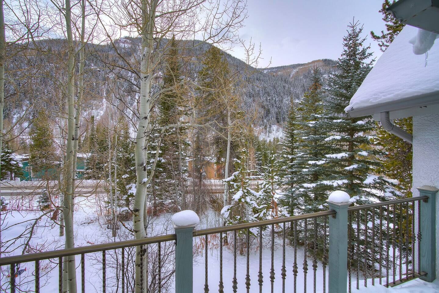 A snowy landscape with a mountain in the background and a building with a balcony.