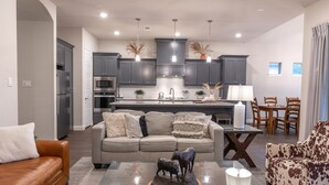 A modern kitchen with grey cabinets, a central island, and pendant lighting.