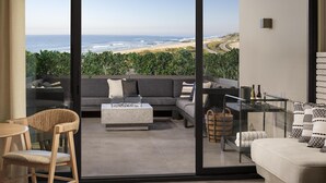 A balcony with a sofa, a dining table, and a view of the ocean.