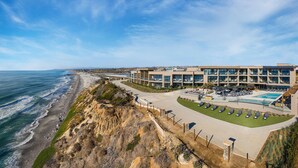 A coastal hotel with a swimming pool, beach access, and a view of the ocean.