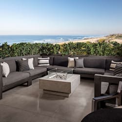 Relax in this stylish outdoor space with a sofa, coffee table, and armchair, offering breathtaking views of the ocean.