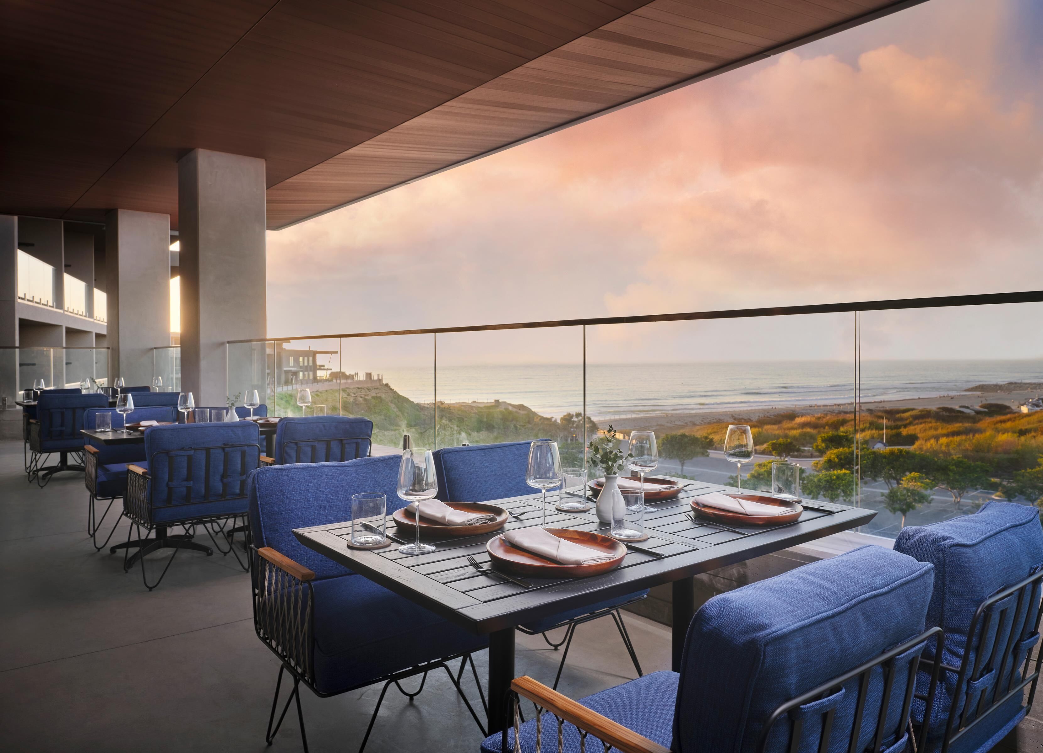 A restaurant with a table set for two, overlooking a coastal view.
