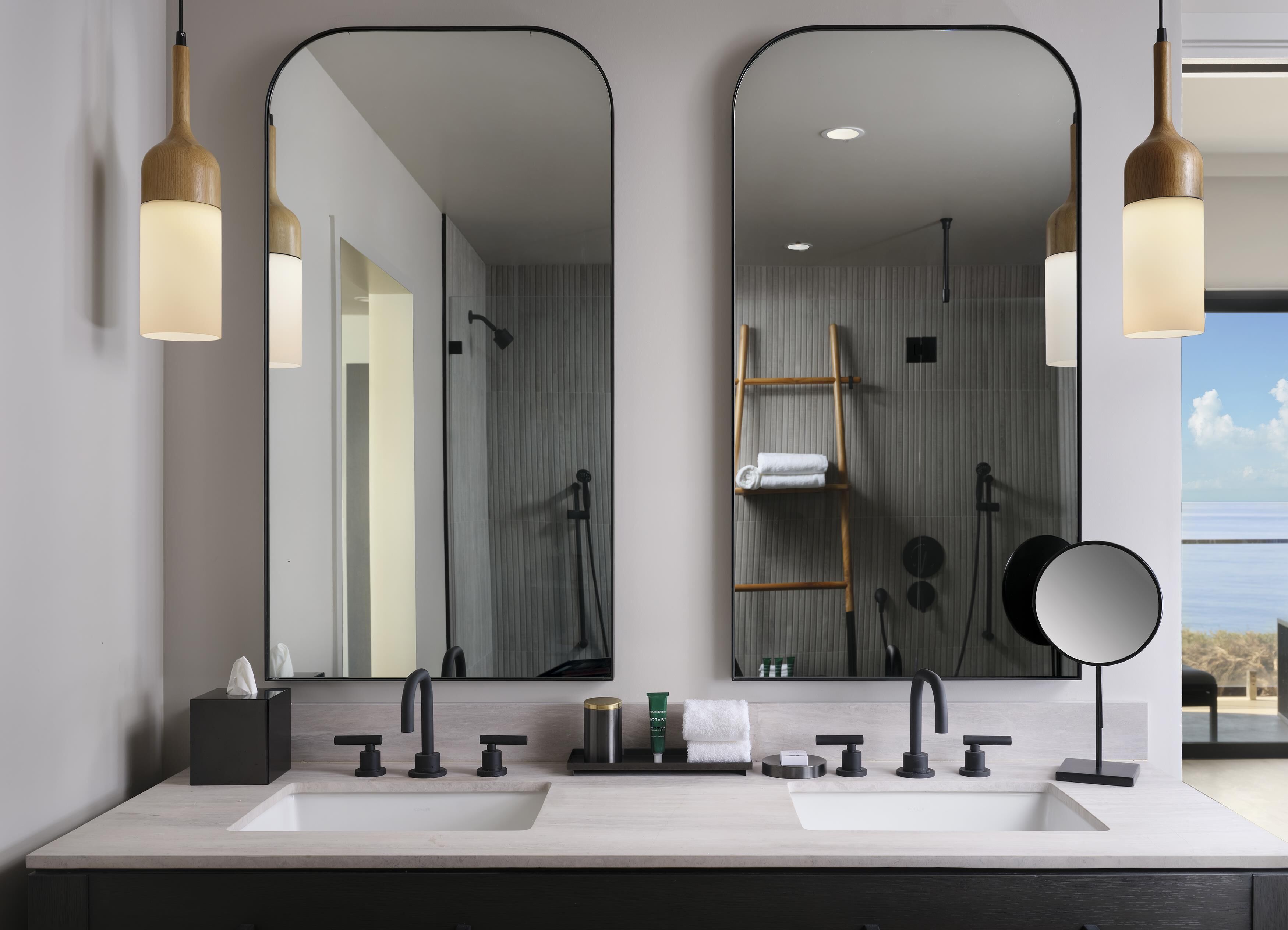 A modern bathroom with two sinks, a mirror, and a shower.