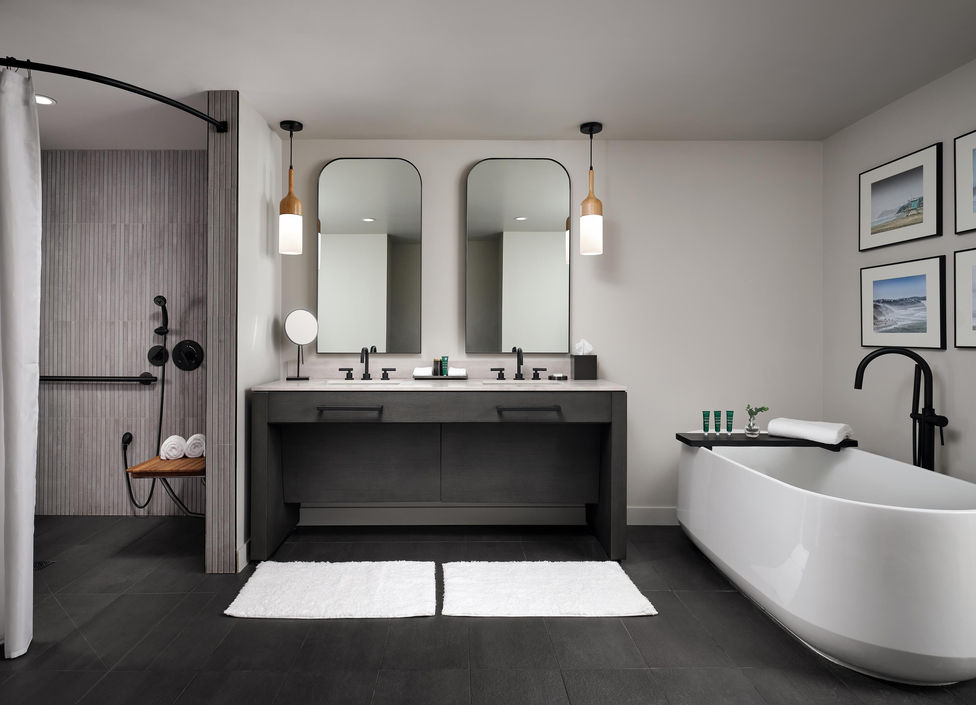 A modern bathroom with a freestanding bathtub, dual sinks, and a large mirror.