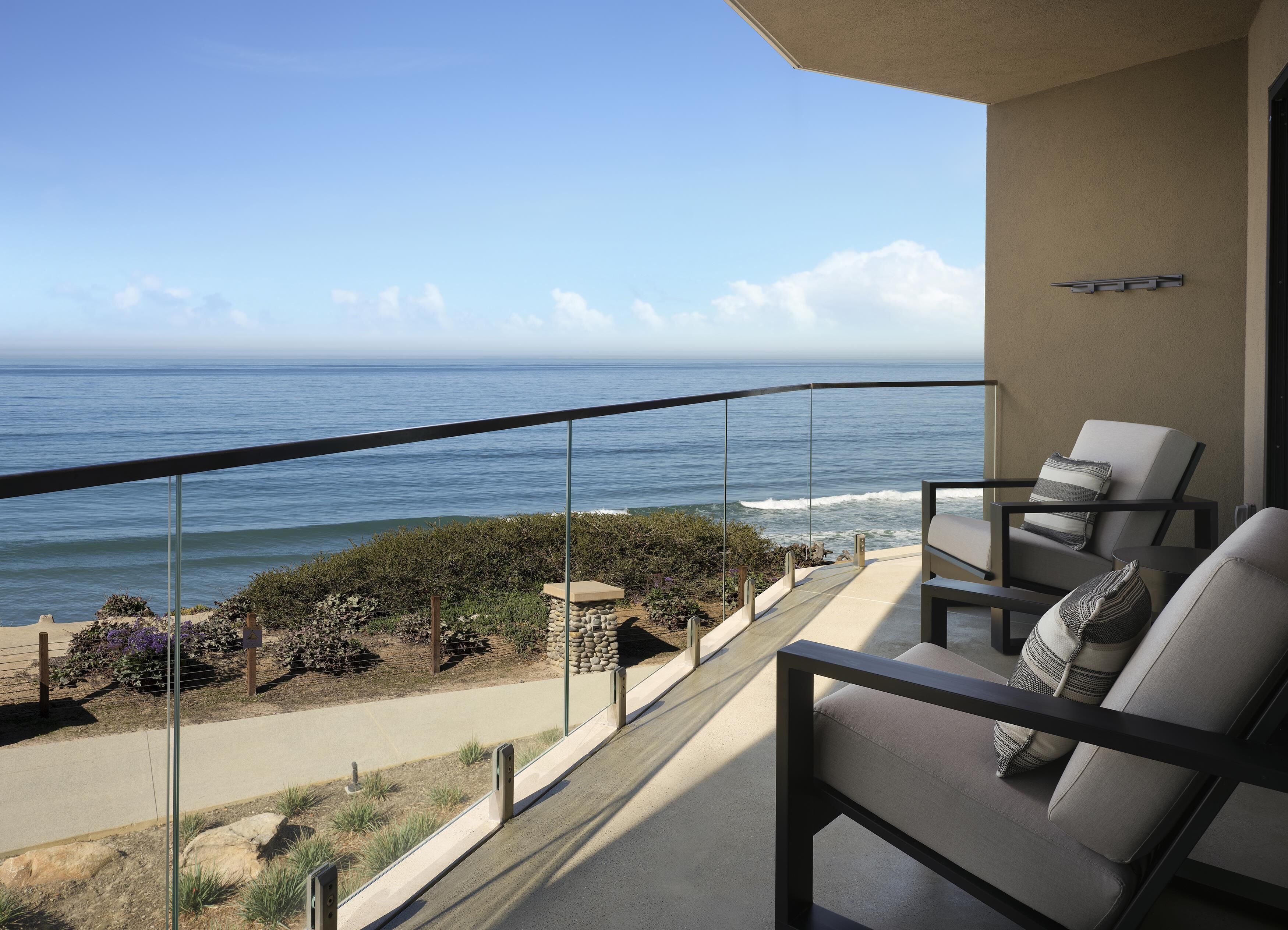 Un balcon avec vue sur l’océan, une chaise et un petit espace jardin.