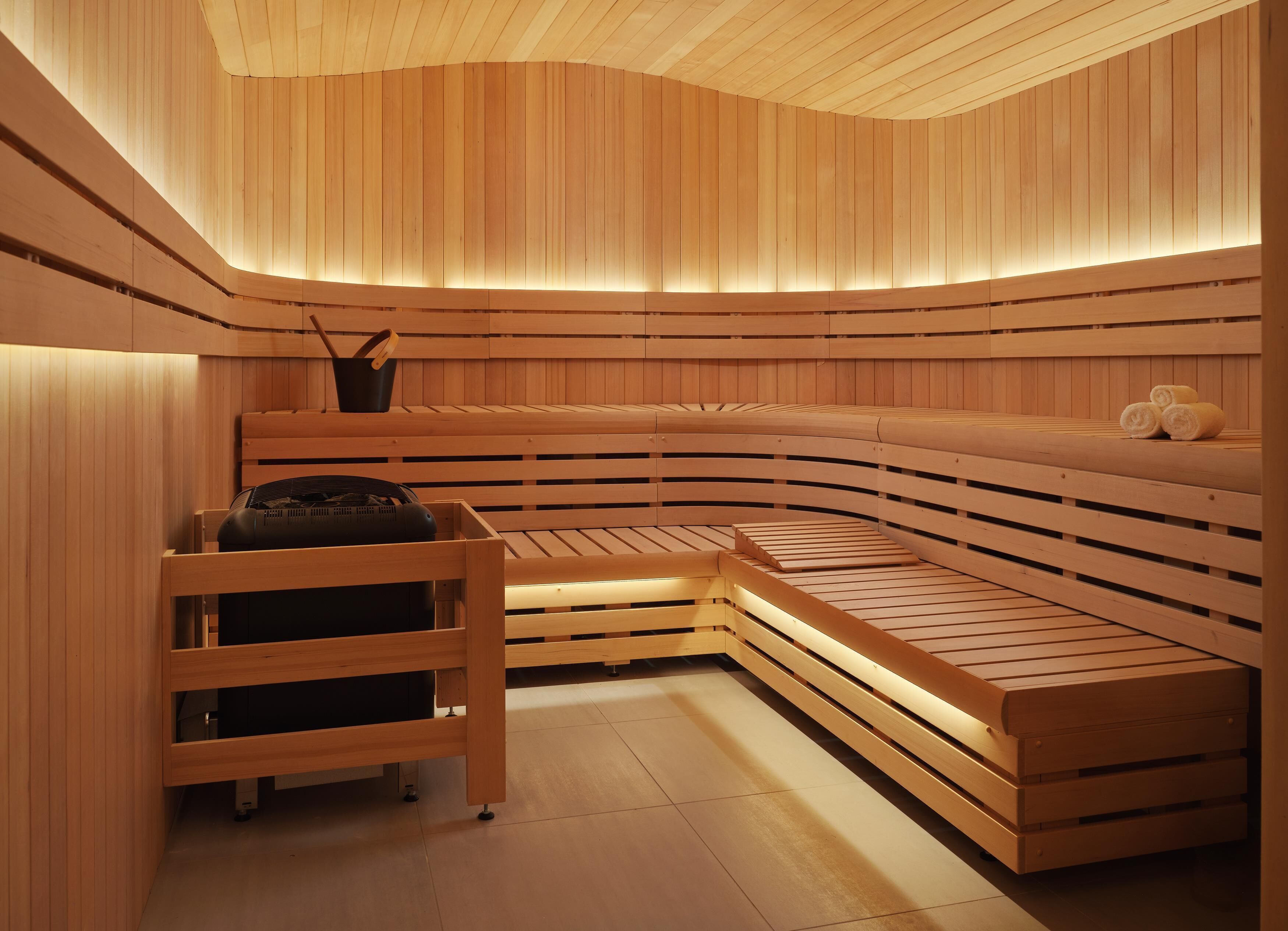 Un sauna avec des bancs en bois et un banc sur lequel se trouve une serviette et un objet noir.