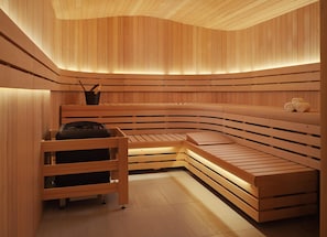 A sauna with wooden benches and a bench with a towel and a black object on it.