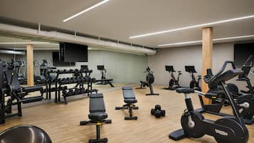 A gym with exercise equipment, mirrors, and a wooden floor.