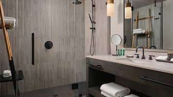 Un baño moderno con un revestimiento de madera, cabina de ducha de vidrio, tocador con espejo y un perchero para toallas.