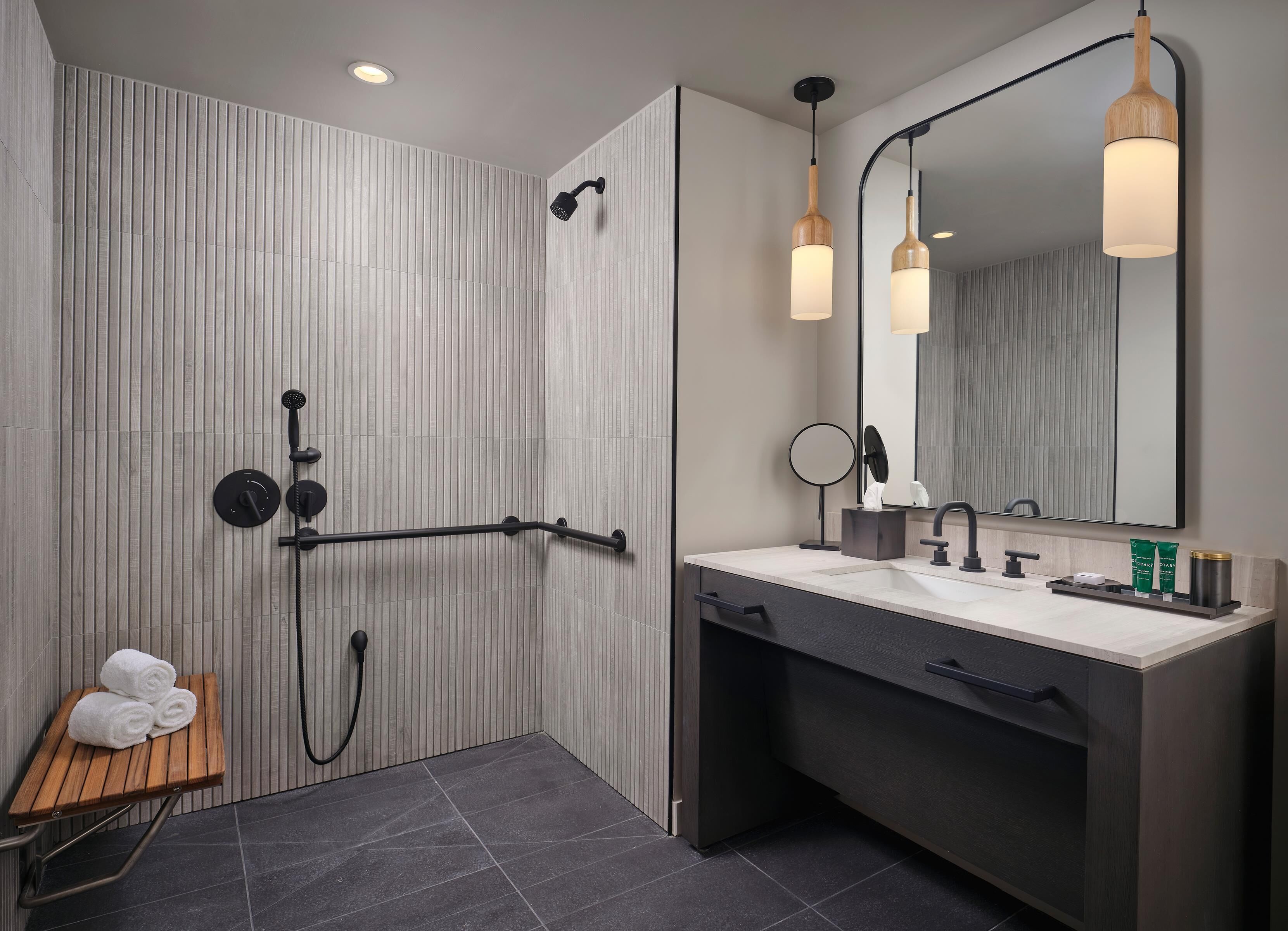 Une salle de bain moderne équipée d’une douche, d’un meuble-lavabo avec miroir et d’un porte-serviettes.