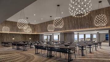 A conference room with round tables and chairs, large spherical hanging lights, and a wooden wall.