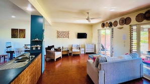 Amplia sala de estar con cocina, comedor y zona de estar con sofá y sillones.