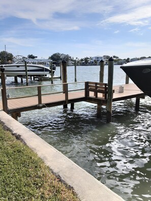 A dock extending into a body of water with a wooden bench and a small table. - Luxury Waterfront Retreat with Private Dock, Golf Cart & Beach Access (Indian Rocks Beach)