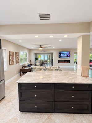 A spacious kitchen with a large island, dark cabinetry, and a ceiling fan. - Luxury Waterfront Retreat with Private Dock, Golf Cart & Beach Access (Indian Rocks Beach)