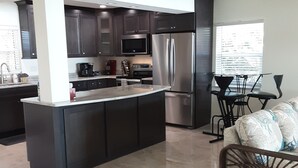 Una cocina moderna con armarios oscuros, electrodomésticos de acero inoxidable y una isla central.