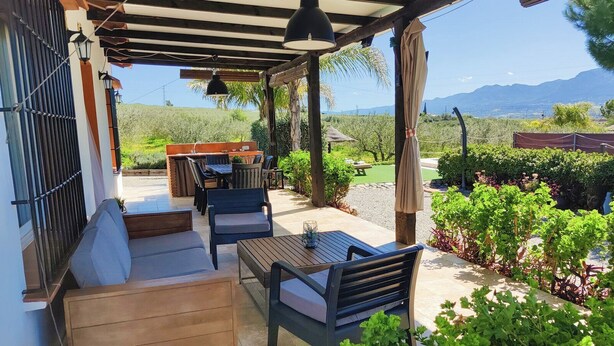 Una veranda esterna coperta con posti a sedere, un tavolo e una zona barbecue.