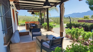 A covered outdoor patio with seating, a table, and a grill area. - Casa Rural Mirasierra Alhaurín el Grande by Ruralidays (Málaga)
