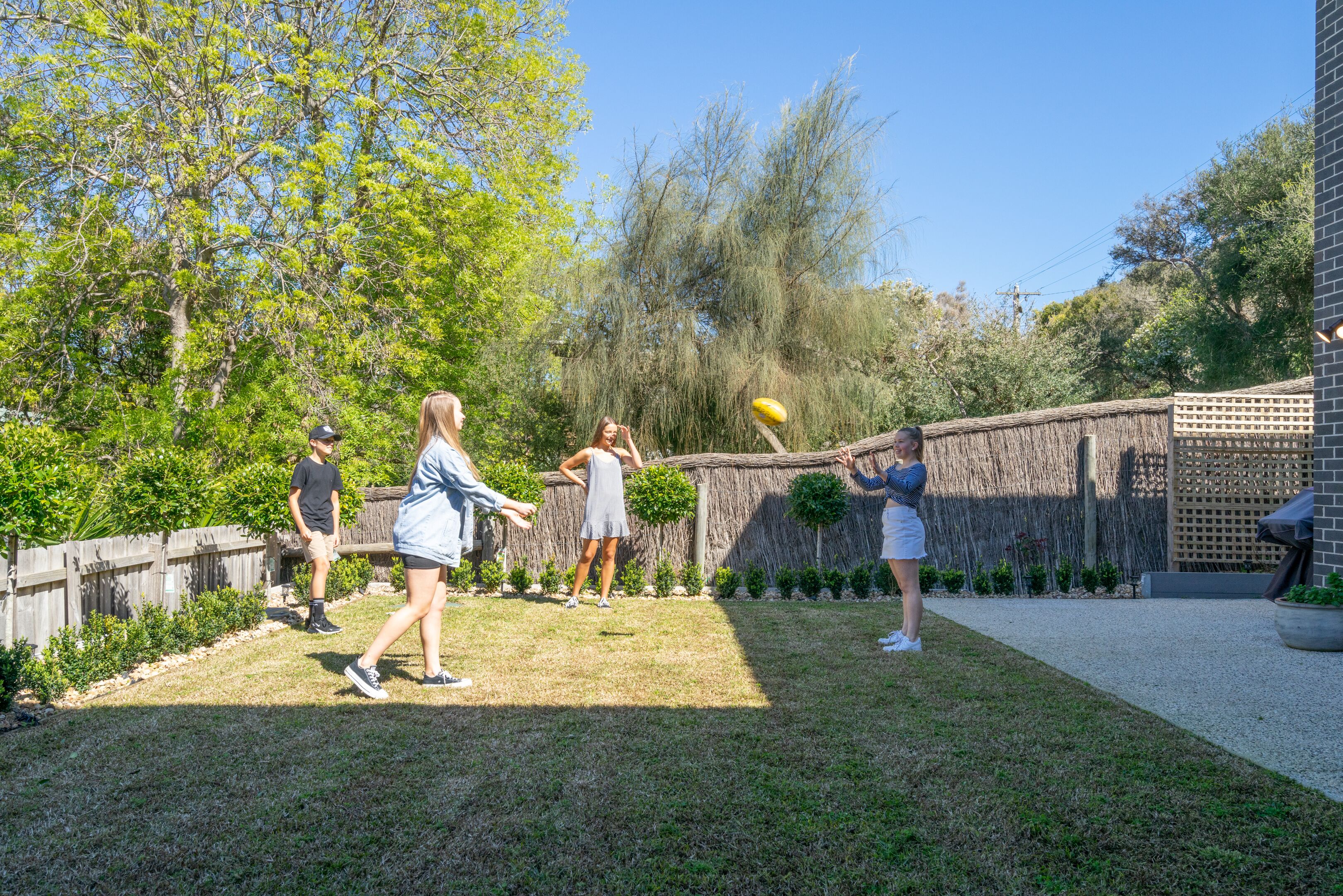 Un jardin avec une clôture en bois, une structure recouverte de chaume et une variété de plantes.
