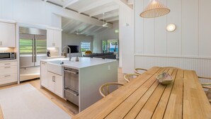 Une cuisine moderne dotée d’un îlot central, d’appareils électroménagers en acier inoxydable et d’une table à manger en bois.