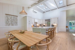 A spacious kitchen with white cabinetry, a wooden dining table, and a large island with seating.