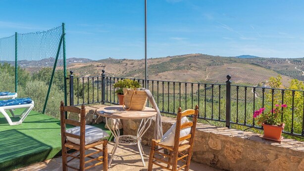 A terrace with a table, chairs, and a view of rolling hills. - Cortijo El Gazpacho Periana by Ruralidays (Málaga)