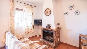 A living room with a sofa, a fireplace, a television, and decorative plates on the wall. - Cortijo El Gazpacho Periana by Ruralidays (Málaga)