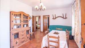 A dining area with a wooden cabinet, a table with chairs, and a chandelier. - Cortijo El Gazpacho Periana by Ruralidays (Málaga)