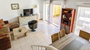 A living room with a sofa, coffee table, TV, and a dining area with chairs and a table.