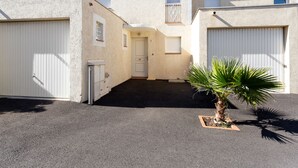 A residential building with a garage, a small entryway, and a palm tree in the driveway.