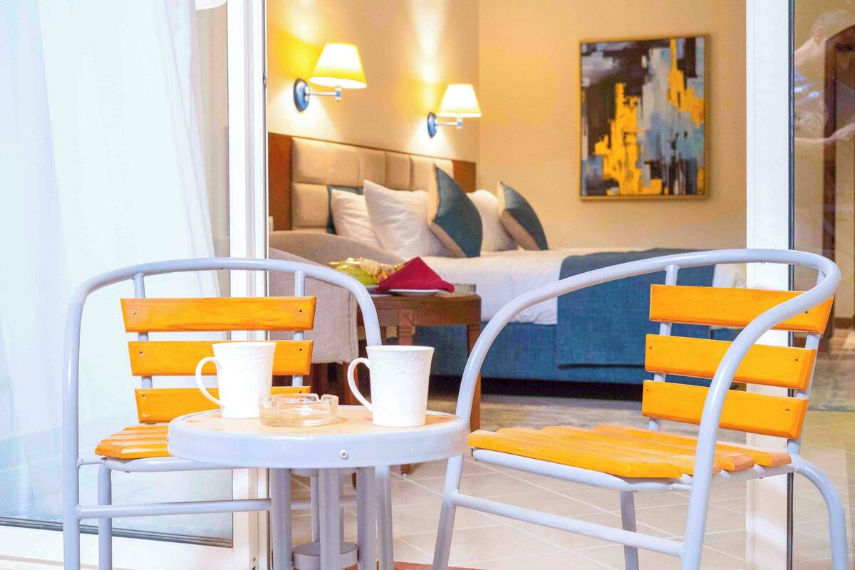 A hotel room with a bed, a bedside table, two lamps, and a painting on the wall.