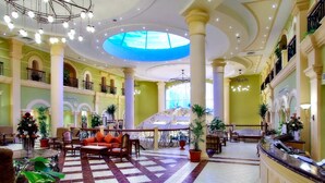 Un vestíbulo de hotel con piso a cuadros, una mesa de recepción y varias áreas de estar.