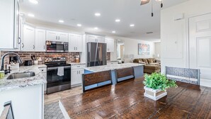 A modern kitchen with white cabinets, stainless steel appliances, and a wooden floor.