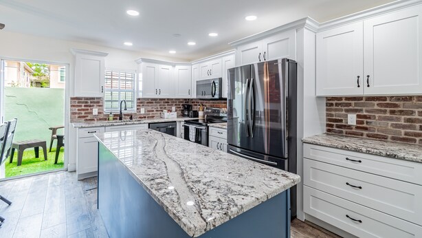 A modern kitchen with white cabinetry, a granite countertop, and stainless steel appliances.