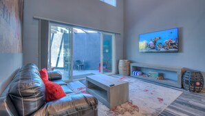 A modern living room with a leather sofa, a coffee table, and a TV mounted on the wall. - Cellar 74: New Modern Wine Casita w/Hot tub (Albuquerque)